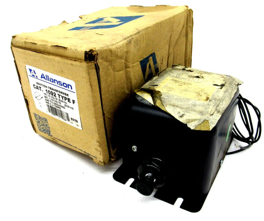 El transformador de encendido ferromagnético Allanson 1092 type f, negro, con etiqueta superior y soportes de montaje, está junto a una caja de cartón marrón gastada con etiqueta y código de barras.