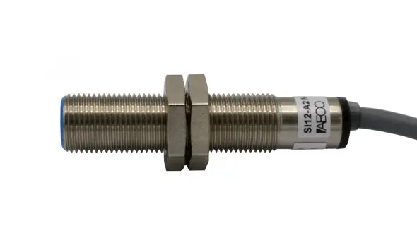 The I12000001 SENSOR DE PROX12MM DIAMSENSA 2MM 20-250 SI12A2 NC is a cylindrical M12 inductive sensor with threaded body, two hex nuts, attached cable, visible label, and IP67 protection for reliable operation.